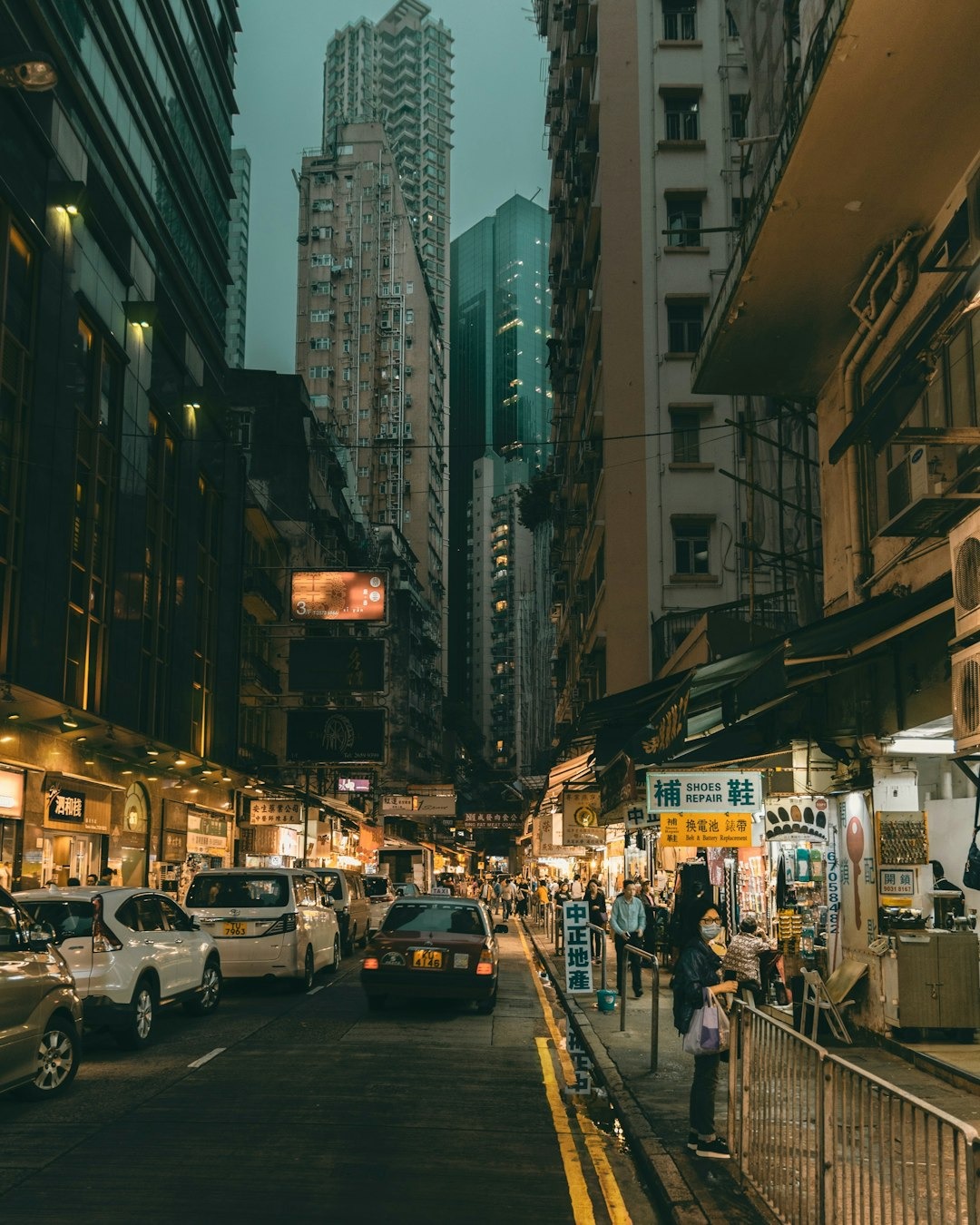 Pedestrians walk along a busy city street lined with shops.